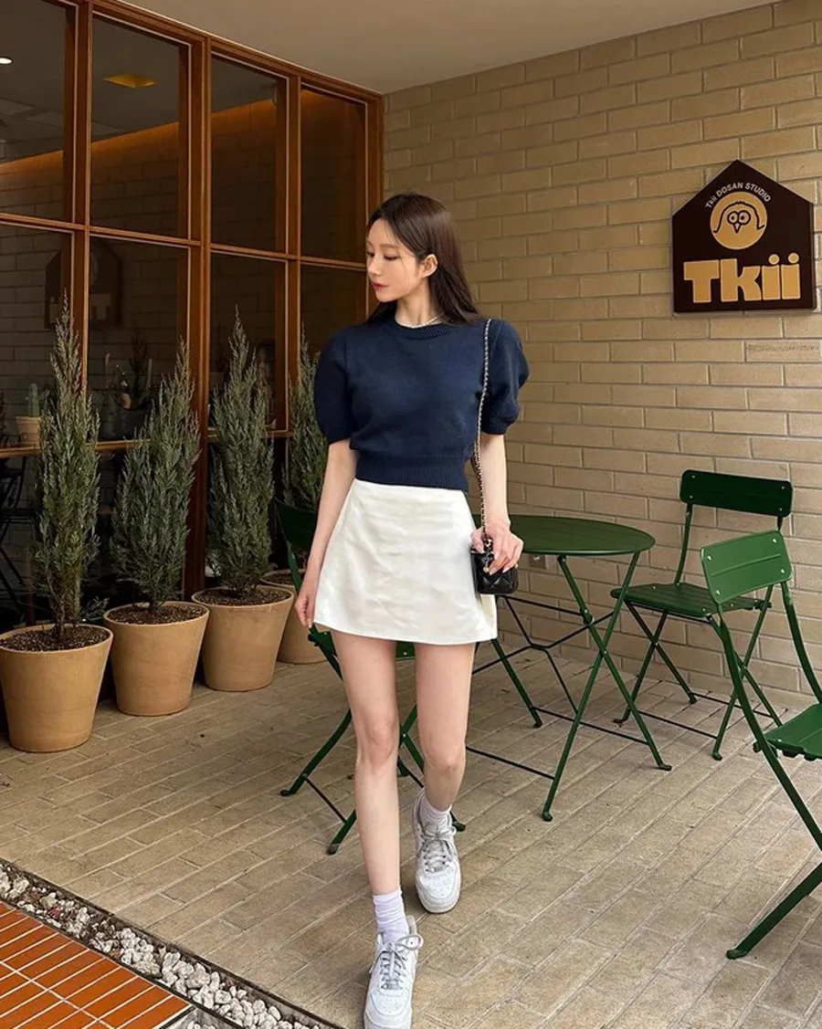 Chân váy ngắn với áo len cộc tay và giày sneaker trắng